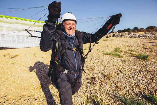 Active senior paraglider on the ground prepairs to fly.