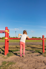 A small child goes in for sports in the stadium. hanging on the horizontal bar, on the uneven bars