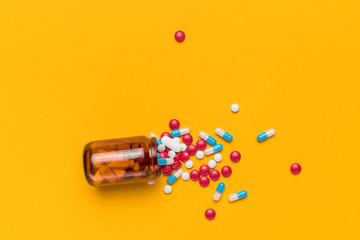 Film coated pills and capsules spilled from bottle, top view
