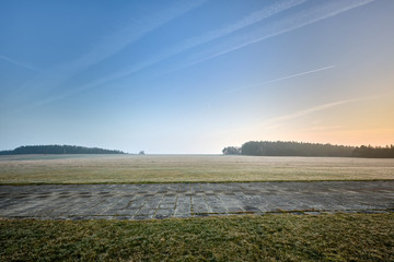 Beautiful countryside landscape with a huge meadow in the foreground in the sunset light in winter....