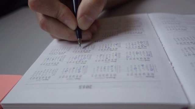 A man makes a date stamp in the calendar diary. Workflow planning. Close up. Marketing the date on the calendar, closeup.