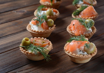 Tartalets with fresh salmon, philadelphia cream cheese, olives on wooden background