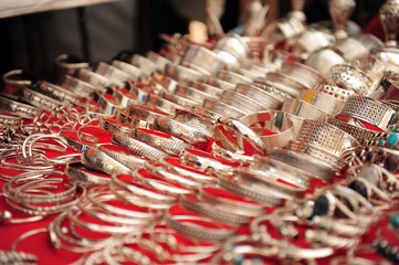 Silver jewelry in the Asian market. Various silver rings and bracelets lie in rows, close-up. Handmade jewelry in the Eastern Bazaar.