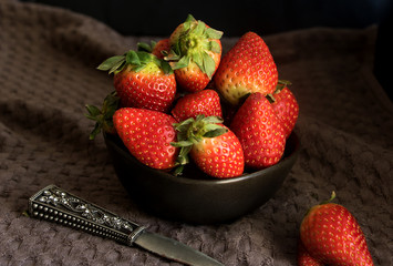 schssel mit frischen erdbeeren vor dunklem hintergrund