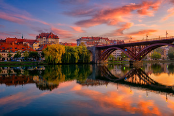 Amazing view of Maribor Old city, Main bridge (Stari most) on the Drava river before sunrise, Slovenia. Scenic cityscape with color sky and reflection, travel background for wallpaper or guide book