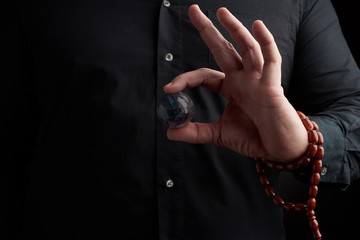 adult man in black clothes holds in his hands a glass magic ball, object for religious rituals