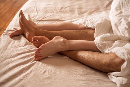 Men's and women's legs stick out from under the blanket.