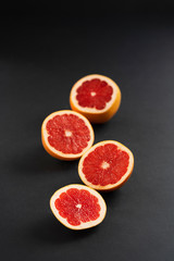 Fototapeta na wymiar citrus fruits cut into slices on a black background, top view, copy space, vertical frame