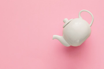 White porcelain teapot on a pink background, minimal art, close-up, flat lay