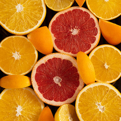 citrus fruits cut into slices laid out in the form of a heart on a black background, top view, copy space, square frame for Instagram