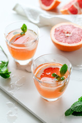 Healthy grapefruit drink with mint on a white marble tray