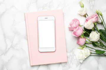 Mobile phone with pink and white roses flowers on marble background.Minimalistic composition for...