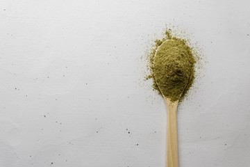 A wooden spoon with hemp flour lies on a light concrete table.