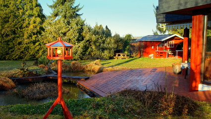 malerischer Garten mit Teich und Gartenhaus im frühen Morgenlicht