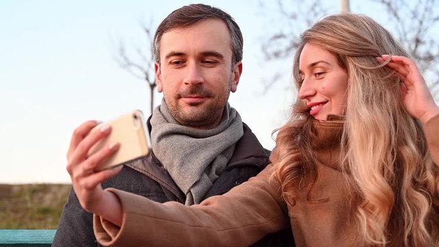 Young man and woman taking a selfie in a public park