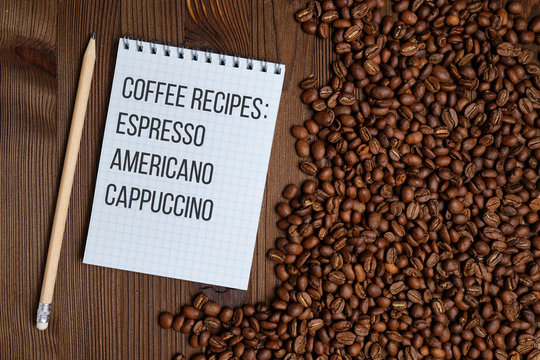 Notebook with recipes of coffee, capcino, Americano, espresso next to coffee beans on a dechy wooden background. Top view.