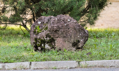A large stone in the park by the road