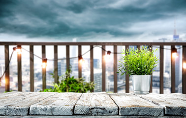 White wooden table of free space and small green plants. City landscape with dark sky and copy space for your decoration. 