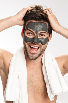 Photo of happy half-naked man with cosmetic mask on his face smiling
