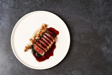 Sliced lamb meat and mashed potatoes on a white plate on gray table