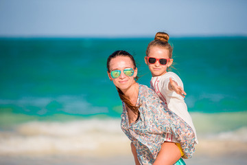 Beautiful mother and daughter at Caribbean beach enjoying summer vacation.