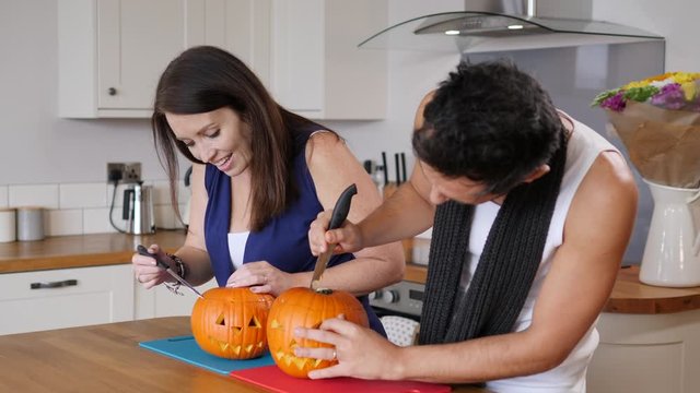 4K: Two people carving Pumpkins with knives to make Jack O Lanterns for Halloween - Slow Motion. Stock Video Clip Footage