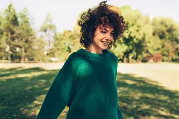 Beautiful young woman smiling posing against nature background with windy curly hair, have positive...