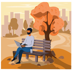 A man works on a laptop in the street while sitting on a bench in an autumn park. The working process.