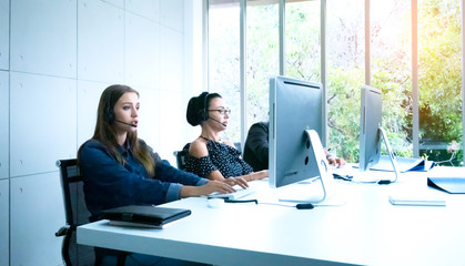 Young woman call center agent in headset consulting online client