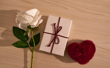 White roses and valentines day cards and free hearts on a wooden table in the top view