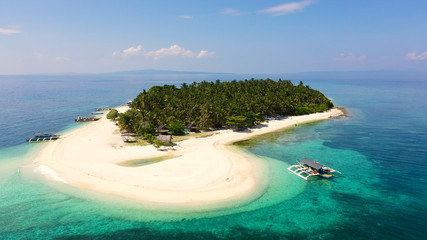 The island of white sand on a large atoll, view from above. Tropical island with palm trees. Seascape with a paradise island. Digyo Island, Philippines. Summer vacation and tropical beach concept.