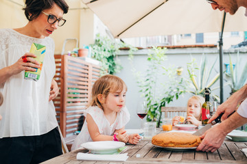 family with female children outdoor sitting table having breakfast