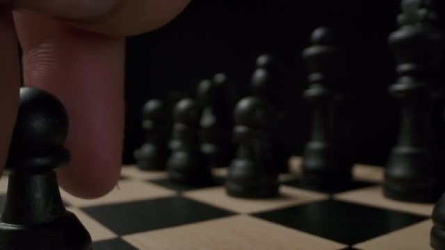 The first standard move by the E7-E5 chess black pawn on checkerboard. Macro wide angle shot with dolly sliding out. Epic beginning of the chess game