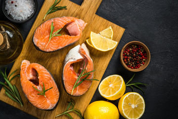 Raw salmon steak on black top view.