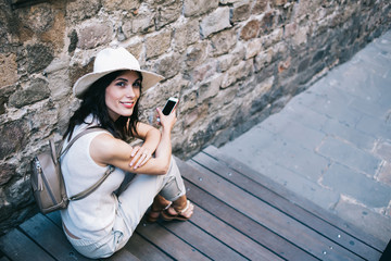 Happy relaxed tourist interacting with smartphone on street against medieval building