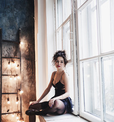 Fototapeta premium High fashion model woman in black lingerie and shoes sitting on window