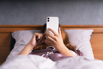woman using phone on bed after wake up - 319442232