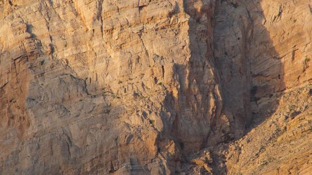 Sunlights on mountain canyon, Stone texture on a mountain face in early morning light, sedimentary mountain limestone rocks texture , Ras Al Khaimah  , United Arab emirates 