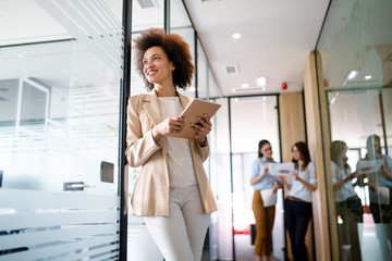 Portrait of an attractive young african businesswoman smiling while standing by windows in office