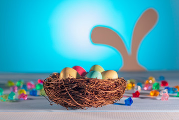 Easter nest, hidden eggs by a hare. Egg hunt. Easter Bunny on a blurry background. Spring religious holiday. Colored Easter eggs. Space for text.