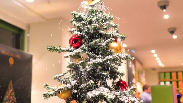 Arbol de navidad con decoraci&oacute;n con bolas rojas blancas y doradas cae nieve artificial