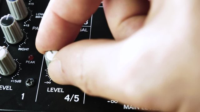 Fine tuning the channel levels on analogue audio mixer. Close up 4k