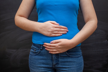 Woman with pain in her stomach on a black background.