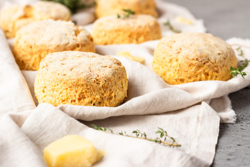 Cheese scones, pieces of cheese and thyme on a grey napkin. Grey stone background, toned image.