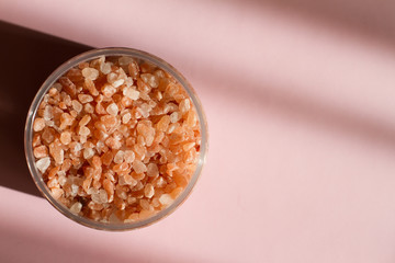 Himalayan salt. Bath salt. Spa treatment. The industry of beauty and relaxation. Scattered salt on a white background. Bath of crystals in a transparent jar. The view from the top. Space for text.