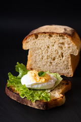 Organic Food breakfast concept homemade Poached egg or eggs benedict on sourdough bread toasted on black slate board