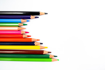 Bunch of different colored wax crayons arranged together making a nice wave while isolated on a white background