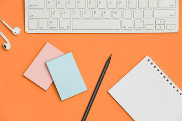 Minimal workplace with blank notepad, keyboard and supplies on colored background. Top view. Flat lay