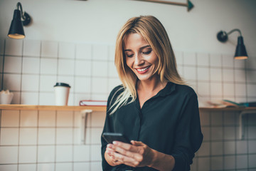 Gorgeous lady in trendy shirt browsing smartphone at home