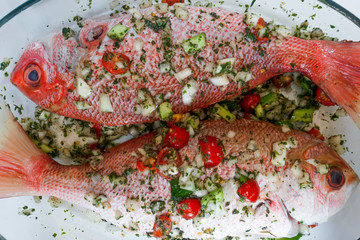 Two raw Red Snappers seasoned with onions, herbs and chillies